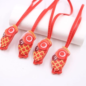 Detail of red leather carp fish pendant with fine stitching and traditional scale pattern
