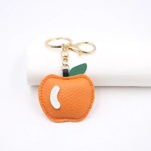 Detailed view of orange faux leather apple keychain with green leaf and gold hardware