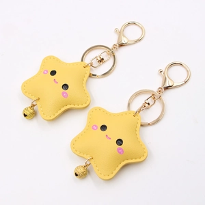 Detail of yellow star keychain with cute smiley face, gold bell, and textured PU leather