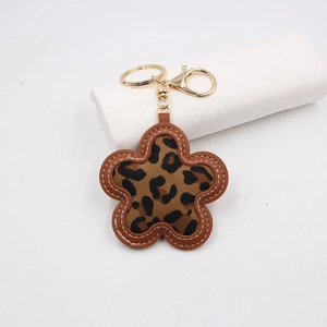 Close-up of leopard print flower keychain with brown leather edges and gold metal clasp