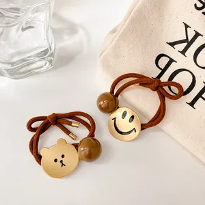 Minimalistische elastische haarelastiekjes met gouden beer en smiley op witte ondergrond