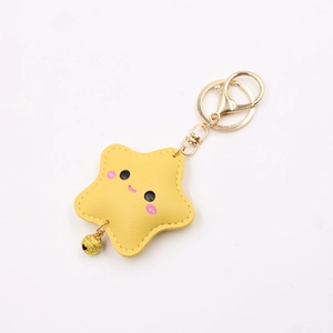 Macro detail of yellow leather star keychain with cute smiley face and golden bell charm