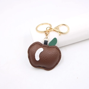 Detailed close-up of brown litchi pattern leather apple keychain with gold metal clasp