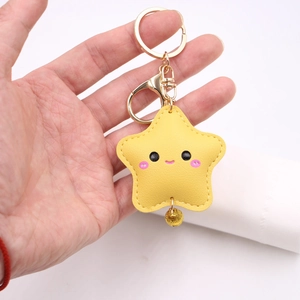 Close-up of yellow star leather keychain with cute face, gold bell and metal clasp
