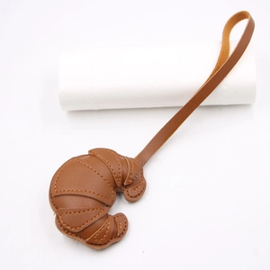 Detail of a brown leather croissant pendant with stitching and long hanging strap
