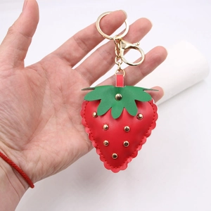 Punk style red leather strawberry keychain with gold studs and metal clasp shown in hand