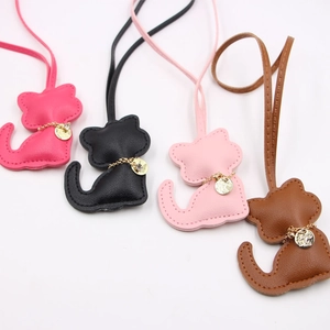Leather cat-shaped bag charms in pink, black, and brown with golden chains and lanyards