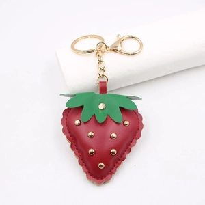 Detail of red leather strawberry keychain with gold studs and metallic lobster clasp
