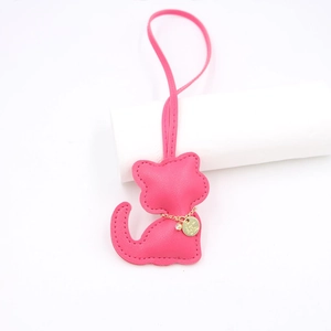Close-up of rose red leather cat bag charm with fine stitching and golden chain details