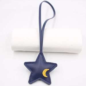Detail of navy blue leather star bag charm with yellow moon patch and blue stitching