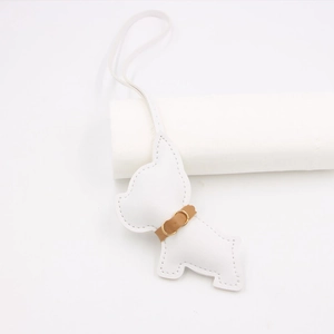 Detail of white leather French Bulldog bag charm with brown collar and gold ring accessory