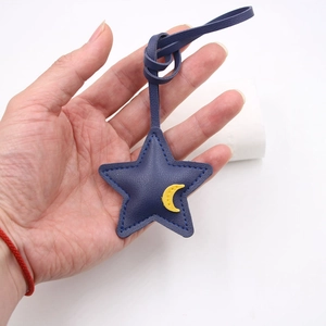 Star and moon leather bag charm accessory with blue star and yellow crescent detail