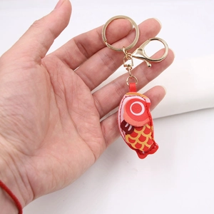 Detailed view of fish-shaped leather keychain with red carp design and gold metal clasp