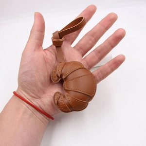 Detailed close-up of a caramel brown leather croissant bag charm with fine stitching texture