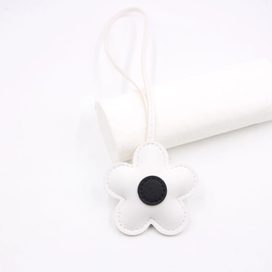 Detail of white leather cherry blossom charm with black center and matching long strap