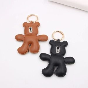 Handmade brown and black leather bear keychains with gold metal rings on white background
