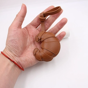 Detailed view of handmade caramel leather croissant pendant with stitching on long strap