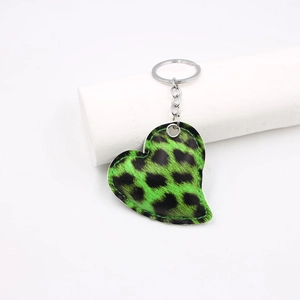 Macro shot of green leopard print heart-shaped leather keychain with silver metal ring