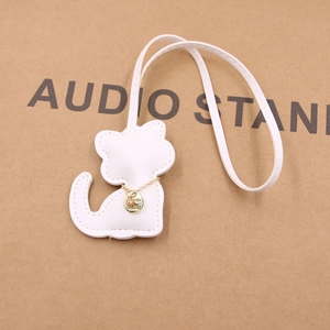 Detailed view of white leather cat charm with fine stitching and gold chain detail