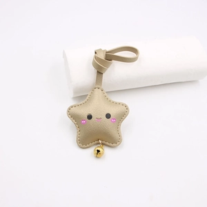 Close-up of champagne gold leather star keychain with cute smiley face and small bell