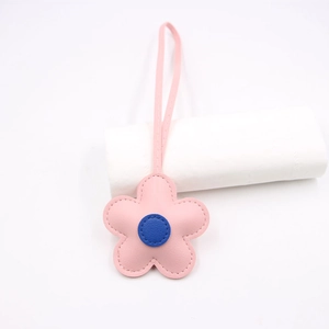 Detailed view of a pink leather flower charm with blue center and matching strap