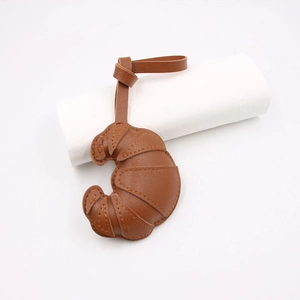 Detailed view of a brown leather croissant pendant with stitching and lanyard accessory