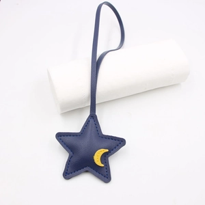 Close-up of a blue leather star charm with a yellow moon patch and fine stitching details