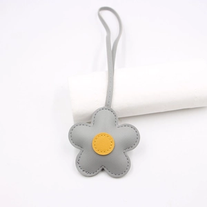 Close-up of grey leather flower bag charm with yellow center and precise stitching