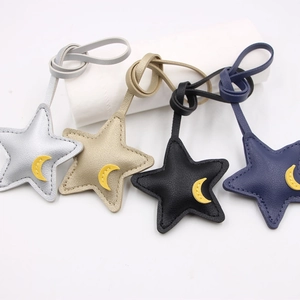 Detail view of four leather star pendants in silver, gold, black and navy blue with moon