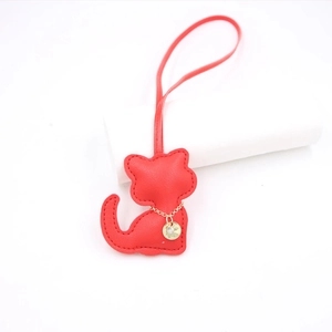 Detailed close-up of a red leather cat bag charm with gold chain and fine stitching