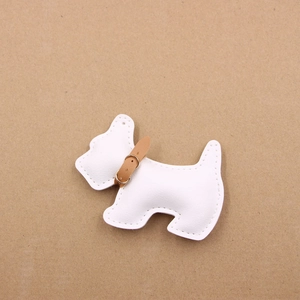 Detailed top view of white leather schnauzer bag charm with brown collar and gold buckle