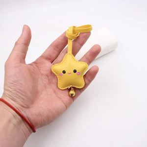 Close-up of yellow PU leather star keychain with cute smiley face and small golden bell