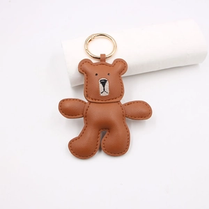 Detailed close-up of a brown leather teddy bear keychain with precise hand-stitched embroidery