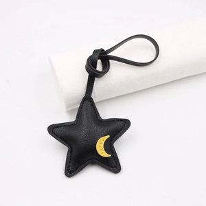 Detail of black star leather bag charm with yellow moon patch and white stitching