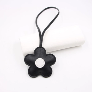 Detail of black cherry blossom leather bag charm with white center and stitching