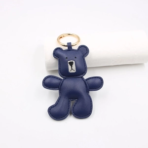 Close-up of deep blue lychee grain leather bear pendant with detailed gold ring clasp