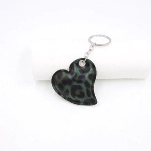 Macro detail of heart-shaped leopard print leather keychain with silver metal ring