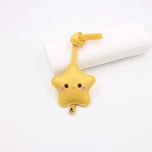 Detail view of yellow star leather keychain with smiling face and golden bell charm