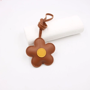 Brown leather flower bag charm with yellow center and stitching detail on a white background