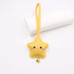 Detail of yellow star leather keychain with cute face expression and golden bell
