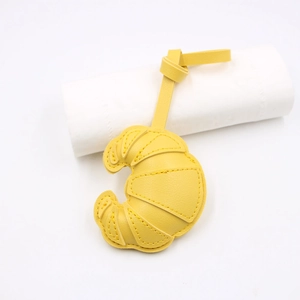 Detailed view of yellow faux leather croissant charm with fine stitching and leather lanyard
