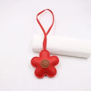 Close-up of red leather flower bag charm with brown center and detailed stitching texture