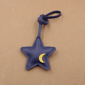 Close-up of a blue leather star keychain with a yellow moon applique and long strap