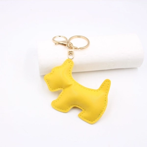 Detail of bright yellow leather dog keychain with gold hardware and stitching