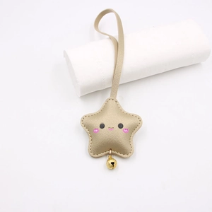 Detail of champagne gold star keychain with lychee grain leather and cartoon smiley face