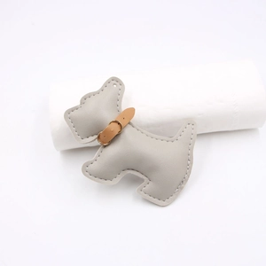 Detail view of a gray leather puppy charm with precise stitching and a brown collar accent