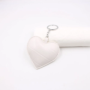 Dettaglio portachiavi a cuore bianco con trama a coccodrillo e anello in metallo argento