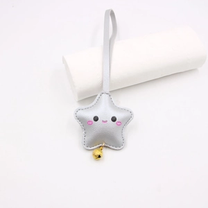 Detail of silver star keychain with cute smiley face, pink blush and golden bell charm