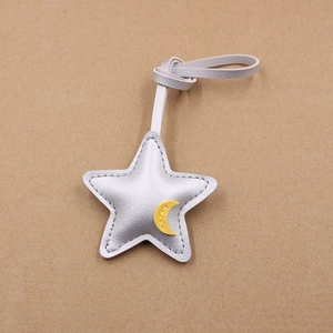Detail view of silver star leather bag charm with yellow moon embroidery and stitching