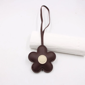 Close-up of dark brown leather flower bag charm with fine stitching and creamy white center